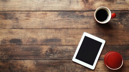 Overhead shot of a tablet, coffee mug, and lid on a wooden table creating a workspace.