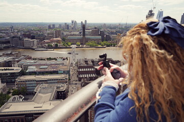 long blonde-haired female tourist takes photos from the top of St. Paul's Cathedral top of the dome...