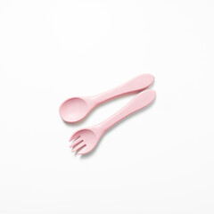 Baby feeding spoon and fork in soft pink. Ideal for baby gear, infant nutrition content, or early childhood care themes.