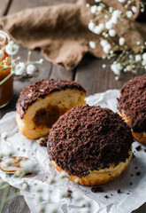 Set of cake donuts with chocolate and condensed milk on wooden background with flowers and cup of coffee. Sweets, dessert and pastry, top view, close up
