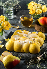 Delicious yellow pear mousse cake with sugar powder on stone background with cup of tea and flowers. Sweets, dessert and pastry, top view
