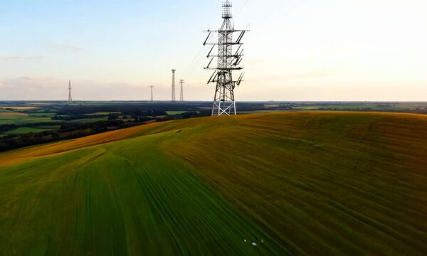 Drone view of a hill with a vast field and a telecommunications tower in the distance. Perfect for landscapes, technology, or rural projects highlighting nature and infrastructure.