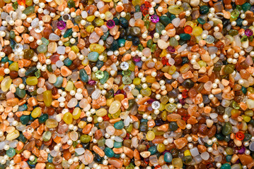 Colorful background of assorted polished gemstones, pearls, and crystals. Bright, vibrant texture of mixed natural stones and beads in various shapes and colors, ideal for abstract backdrop