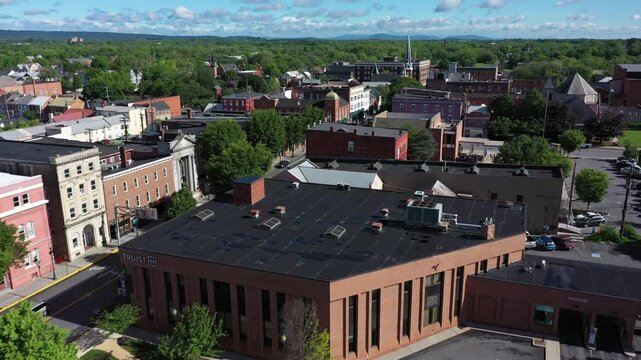 Backing away aerial view showcases the architectural beauty of Berkeley County Courthouse in Martinsburg, West Virginia, surrounded by lush greenery and clear skies.