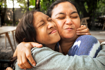 Asian family love and affection between a mother and teenage daughter, hugging one another with...