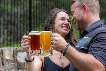 Couple celebrating and cheering with beer pints for National Beer Lover's Day.
