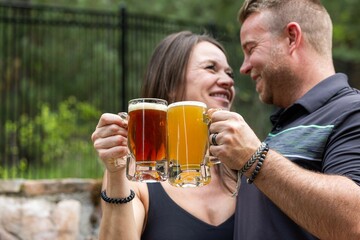 Couple celebrating and cheering with beer pints for National Beer Lover's Day.