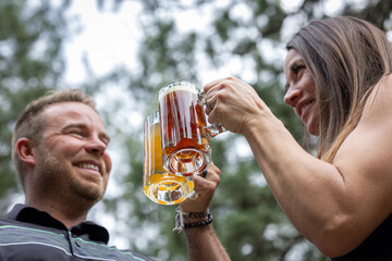 Couple celebrating and cheering with beer pints for National Beer Lover's Day.