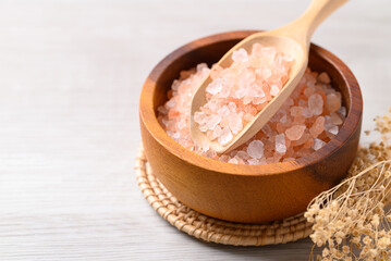 Organic Himalayan pink salt in wooden bowl with scoop on white table, Healthy food ingredient