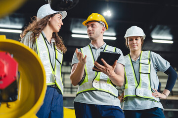 Industrial engineers collaborate in a high-tech factory environment, inspecting robotic machinery...