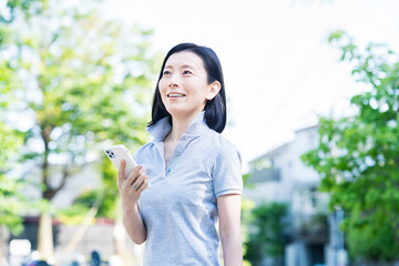 屋外でスマートフォンを操作する中年女性