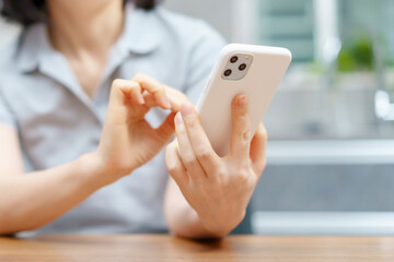 室内でスマートフォンを操作する女性