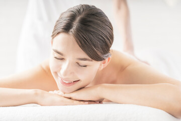 Fototapeta premium 明るい雰囲気のエステサロンでマッサージを受ける若い女性