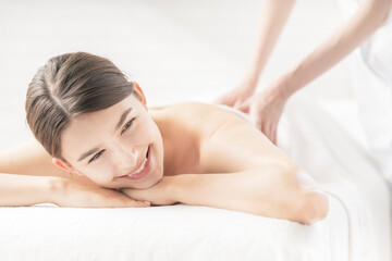 明るい雰囲気のエステサロンでマッサージを受ける若い女性