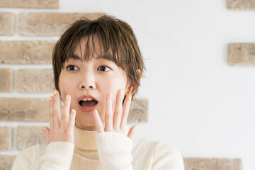 両手で驚きのポーズをする若い女性