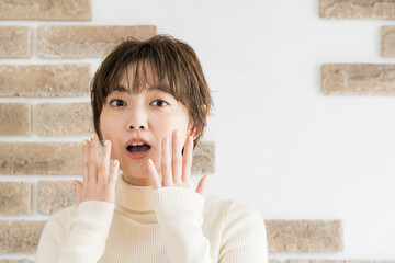 両手で驚きのポーズをする若い女性