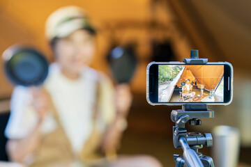 テントの中でスマートフォンで撮影する若い女性キャンパー