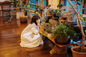 笑顔で観葉植物の様子を見る若い女性