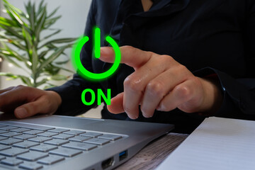 A businesswoman working on a laptop points to a green power icon and the word 