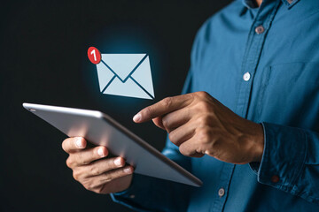 Man checking email on tablet with notification icon against a dark backdrop