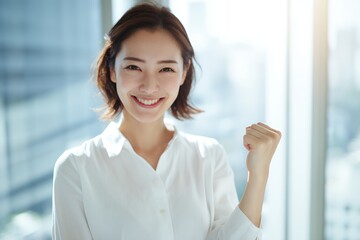 窓際でガッツポーズをする快活な若い女性
