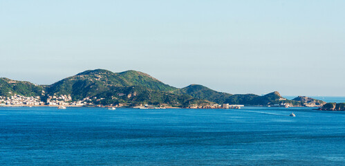 Serene Coastal Panorama with Lush Green Hills and Calm Waters