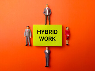 Miniature people and sticky note with the word Hybrid Work on a orange background