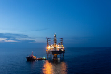 Aerial view of offshore jack up drilling rig during sunset - oil and gas industry.