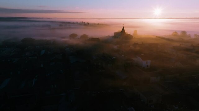 Misty Sunrise Above a Medieval Village, Drone view of village rooftops at dawn in the mist