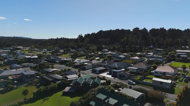Quiet housing area of Moana Town near Lake Brunner, New Zealand. Sunny day with blue say and forest trees in distance. Aerial wide shot.