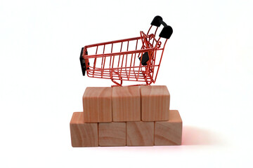 Shopping cart and wooden blocks on white background