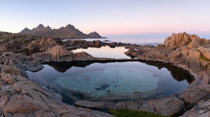 A tranquil sea rock pool reflects the mountain landscape perfectly