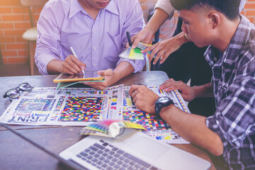Team graphic designer checking print quality of media graphics proof print and color guides in...