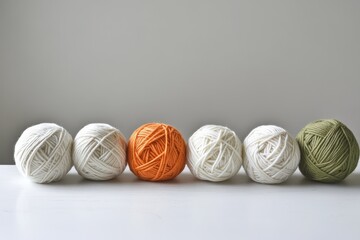 Threaded Balls of Cotton Yarn in Warm Colors on a White Table for Knitting Hobby