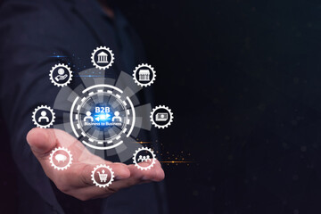 A businessperson's hand presents a digital B2B (business-to-business) network interface with technology icons on a dark background.