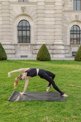 A woman is practicing yoga outdoors on her mat, beautifully showcasing her flexibility and strength amidst an incredibly stunning and serene location surrounded by natures greenery and tranquility