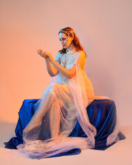 Fantasy studio portrait of a red-haired mermaid faery model wearing a white pearl gown, fairytale...