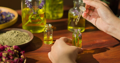 Essential oil is flowing from the dropper into the glass bottle, there are fresh lavender flowers inside the bottle. Plant soaking therapy in essential oils to prepare natural nutrient solution.