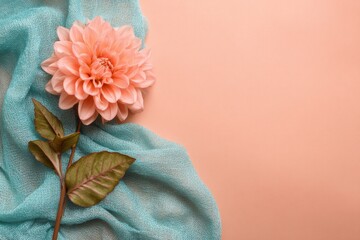 Peachy dahlia atop a teal fabric backdrop.
