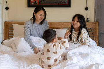 Happy family playing on bed in hotel bedroom