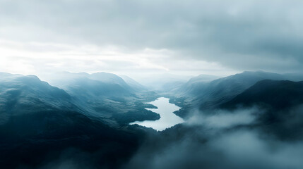 Aerial view of a river winding through misty mountains under a cloudy sky.