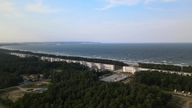 Aerial view of Prora&rsquo;s historic buildings along R&uuml;gen&rsquo;s coast, facing the vast Baltic Sea with lush forests behind.