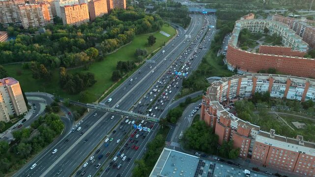 Top-down aerial shot of Madrid&rsquo;s M-30 highway during sunset, showing heavy traffic, residential blocks and green areas. Ideal for themes of mobility, congestion and city infrastructure