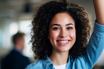 A cheerful woman with a bright smile and curly hair appears confident and content in a professional environment, radiating positivity and approachability.