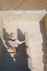 Pretty Asian woman wearing fashionable clothes, casual dress, brown earth tone colors, poses at Adobe house in the local countryside. Architectural mud hut of clay.