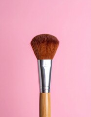 Close-up photo of a makeup brush on a pink background