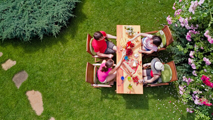 Family and friends eating together outdoors on summer garden party in park. Aerial view of table with food and drinks on grass from above. Leisure, holidays and picnic concept