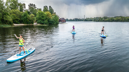Active family on SUP, standing up paddleboards, river water adventure, summer family sport, aerial drone view from above