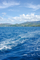 Fototapeta premium A beautiful view of mountains range in Coron, Palawan, Philippines in the summer. Deep blue ocean with piles of waves from the ferry boat is a symbol starting a journey and new adventure