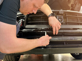 A car wrapping specialist applies a polyurethane film to the car. Selective focus. PPF protective...